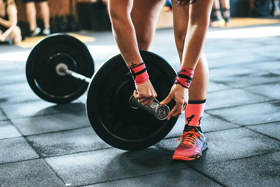 person at gym adjusting weights on floor