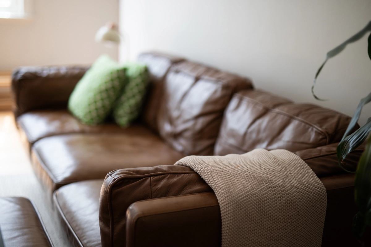 Brown leather sofa with cushions and knitted throw in a living room