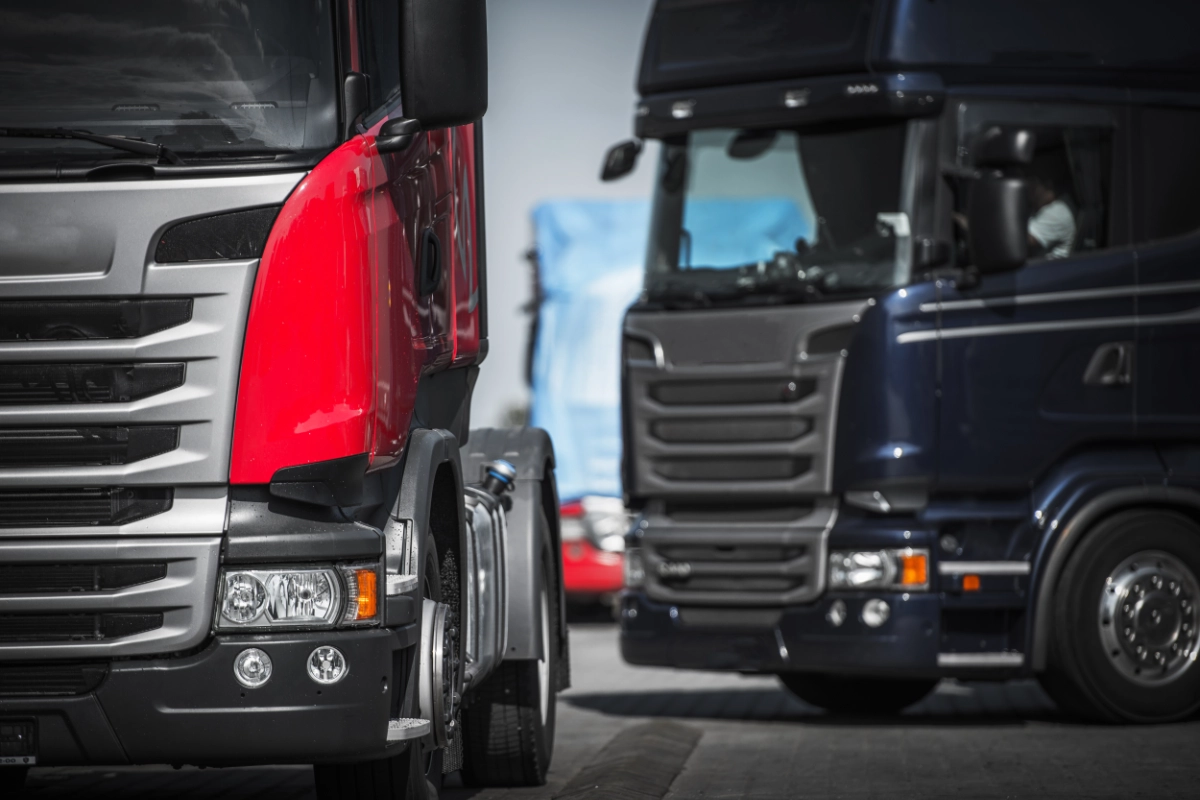 Red and blue HGV lorries parked together in a commercial vehicle fleet