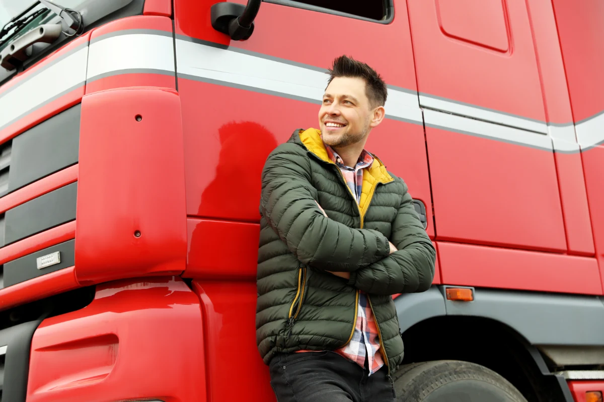 HGV driver standing beside a red commercial lorry