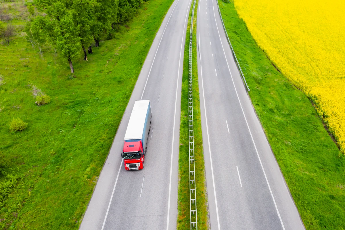 Red HGV lorry travelling along a motorway through the countryside