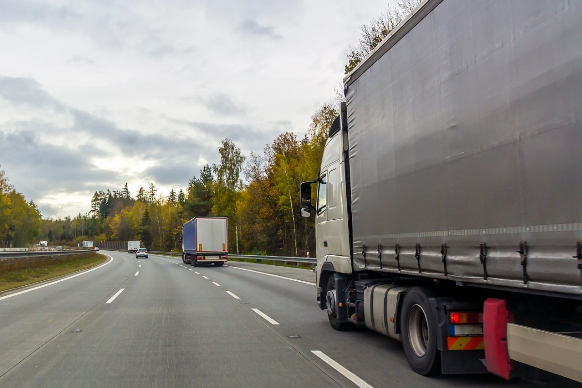 HGV lorries travelling along a motorway through a wooded area