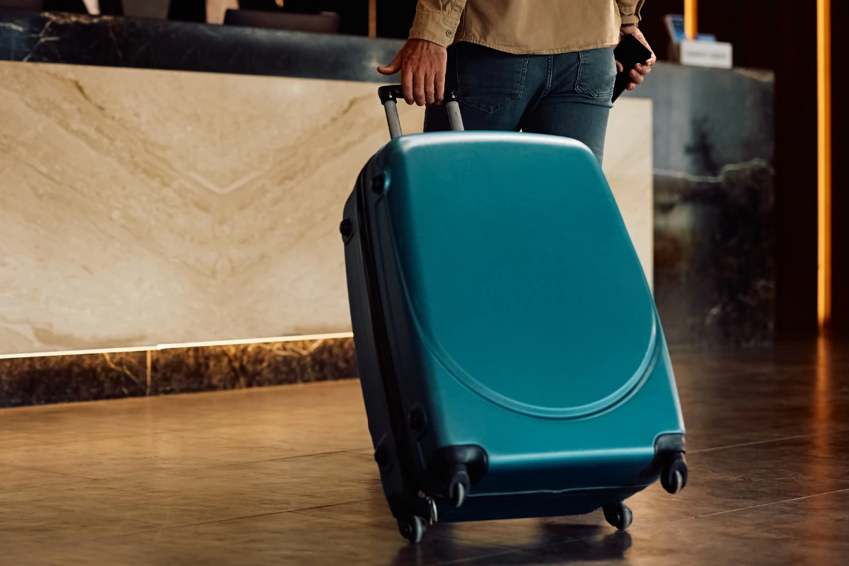 Hotel guest arriving at reception with a suitcase