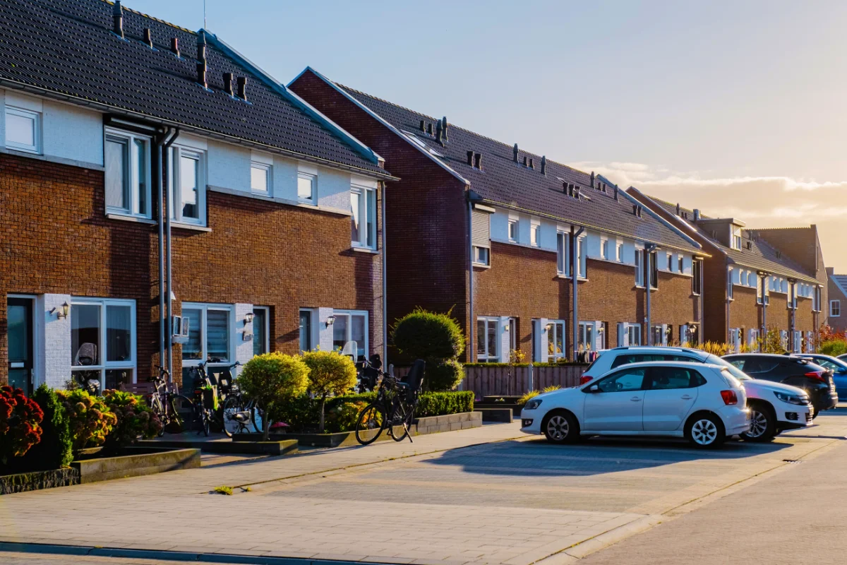 Modern residential housing estate with parked cars along the street