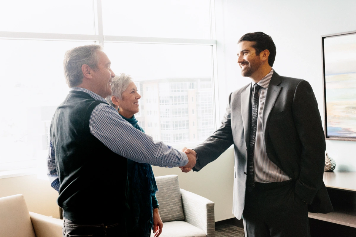 Business professional shaking hands with a couple during a meeting