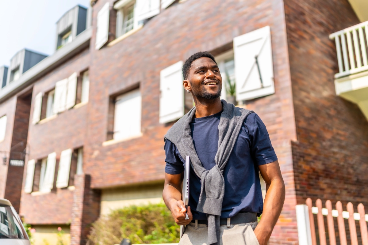 Man holding a laptop outside a modern residential building