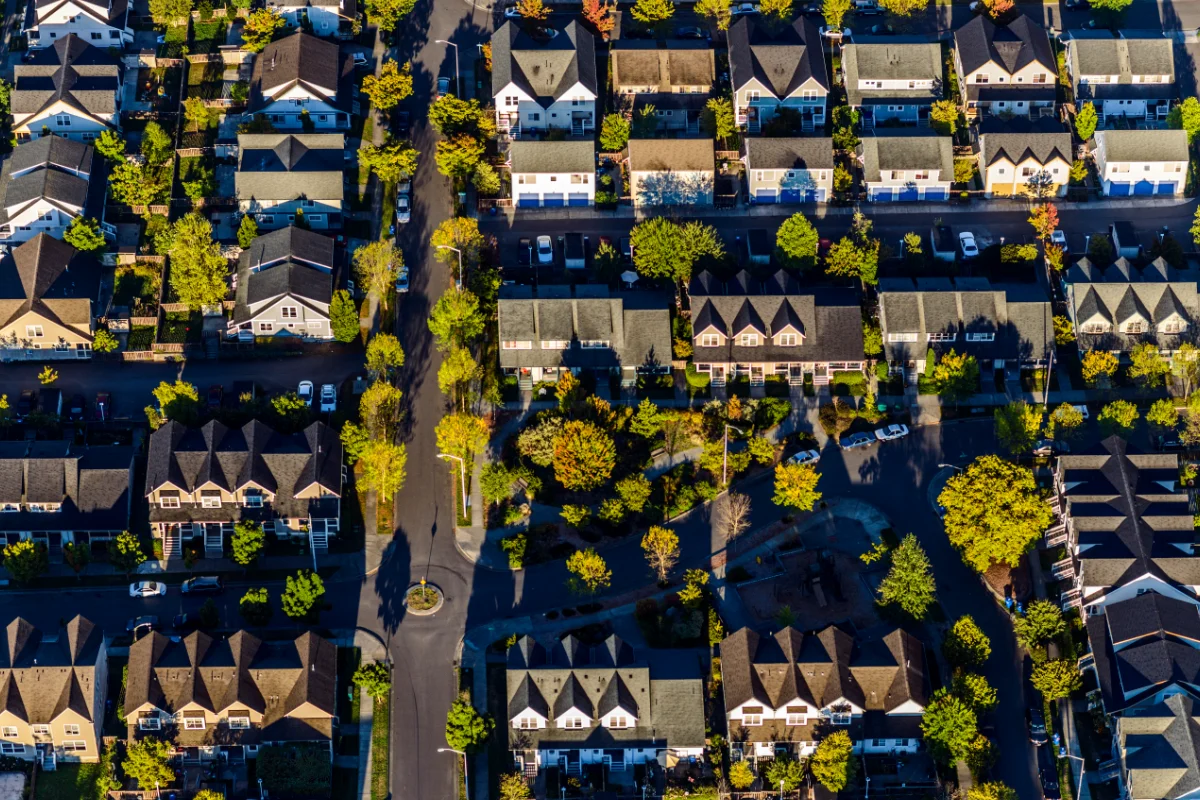 Aerial view of a residential neighbourhood with rows of houses and tree-lined streets