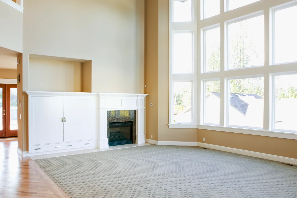 Bright empty living room with large windows and fireplace